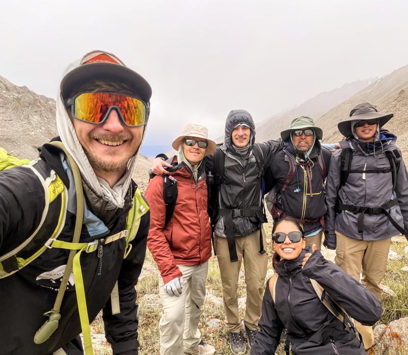 Trevor at the front of a trekking group in waterproofs on a high
                    cloud-covered mountainside.
